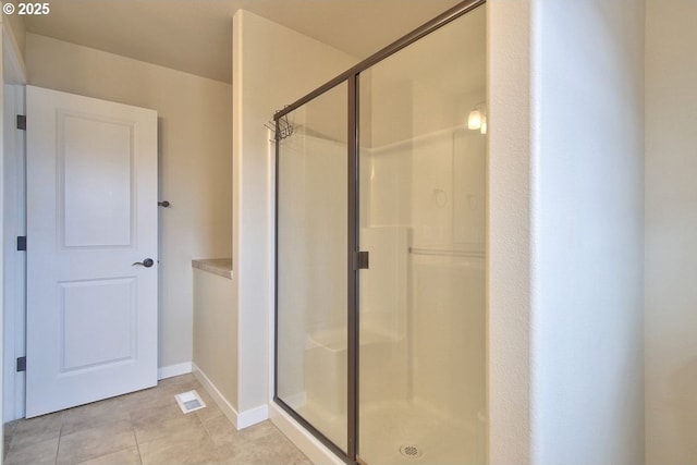 bathroom with tile patterned flooring, visible vents, a shower stall, and baseboards