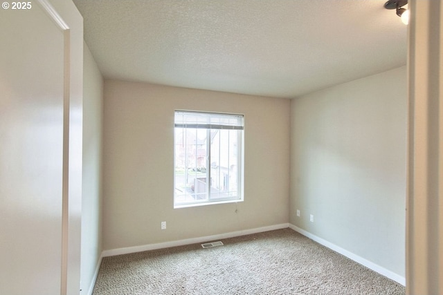 carpeted empty room featuring visible vents, baseboards, and a textured ceiling