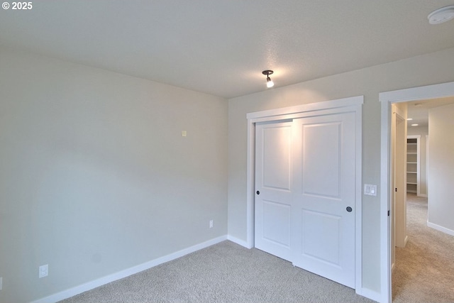 unfurnished bedroom featuring a closet, light colored carpet, and baseboards