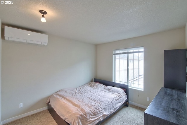 carpeted bedroom featuring a wall unit AC, baseboards, and a textured ceiling