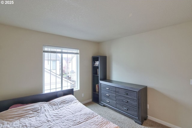 bedroom with a textured ceiling, baseboards, and light carpet