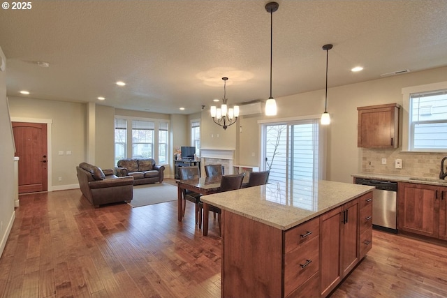 kitchen with a healthy amount of sunlight, wood finished floors, a sink, decorative backsplash, and stainless steel dishwasher