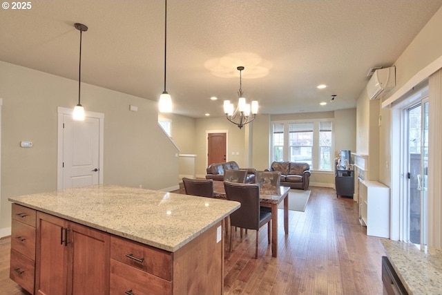 kitchen with open floor plan, light stone countertops, light wood-type flooring, and a wall mounted air conditioner