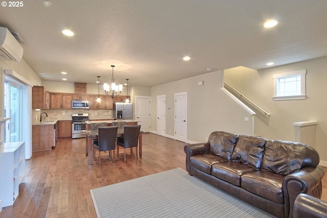 living area featuring a wall unit AC, a notable chandelier, wood finished floors, and recessed lighting