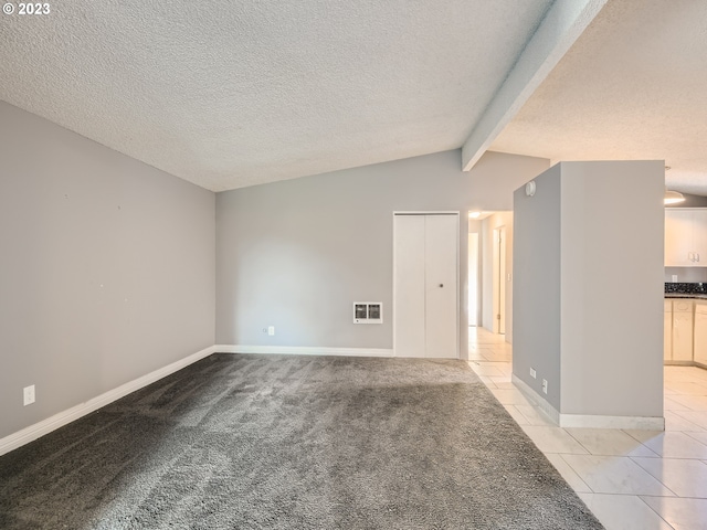 carpeted empty room featuring lofted ceiling with beams and a textured ceiling