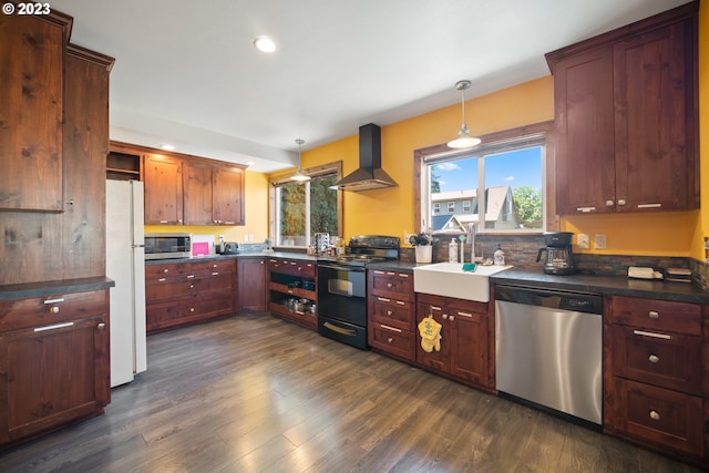 kitchen with decorative light fixtures, appliances with stainless steel finishes, dark hardwood / wood-style floors, wall chimney range hood, and sink