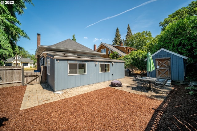 rear view of property with a patio area and a storage shed