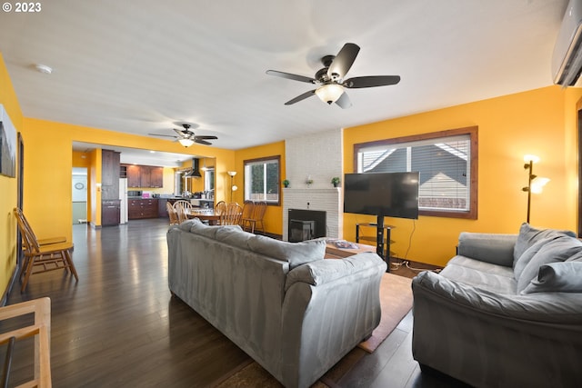 living room with brick wall, a wall unit AC, ceiling fan, a fireplace, and dark wood-type flooring