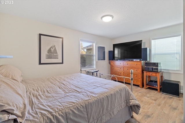 bedroom with a textured ceiling and light wood-type flooring