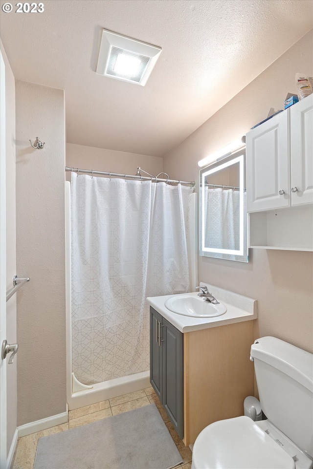 bathroom with a shower with shower curtain, tile patterned flooring, vanity, and toilet