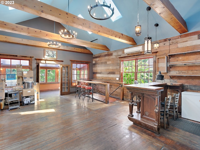 interior space featuring an inviting chandelier, dark wood-type flooring, wood walls, a high ceiling, and a wall unit AC