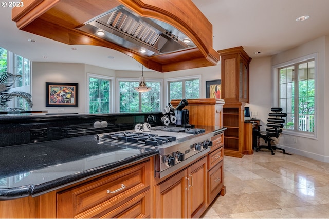 kitchen with dark stone counters, pendant lighting, light tile floors, and a wealth of natural light