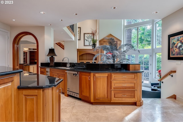 kitchen featuring dark stone countertops, sink, light tile floors, and dishwasher