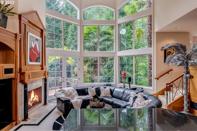 living room with a towering ceiling, a wealth of natural light, and a high end fireplace