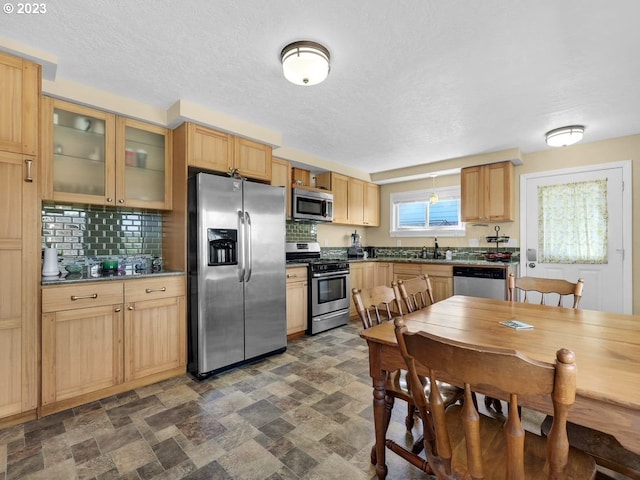 kitchen featuring tasteful backsplash, stainless steel appliances, sink, and dark tile flooring