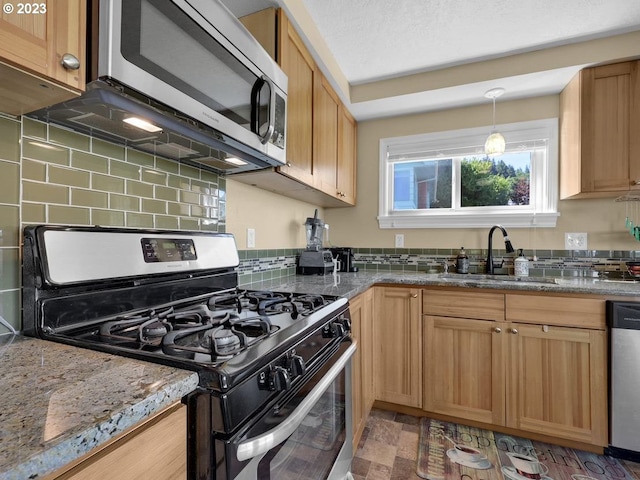 kitchen with pendant lighting, sink, appliances with stainless steel finishes, backsplash, and light stone countertops