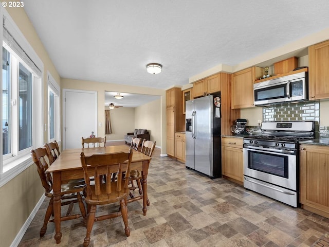 kitchen featuring dark tile flooring, tasteful backsplash, stainless steel appliances, and a healthy amount of sunlight