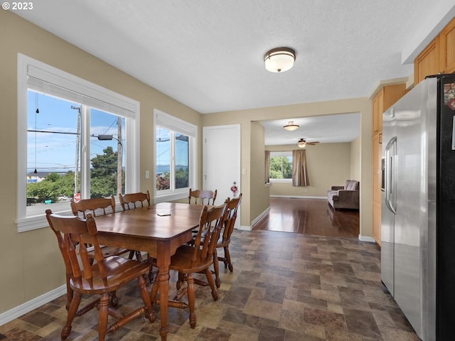 dining area featuring a wealth of natural light, dark tile floors, and a textured ceiling