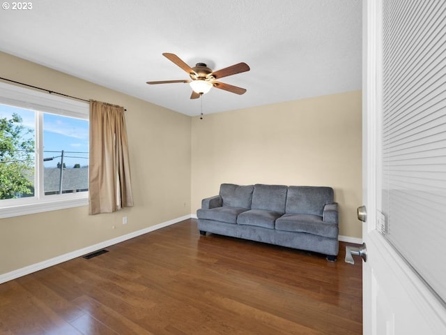 living room featuring ceiling fan and dark wood-type flooring