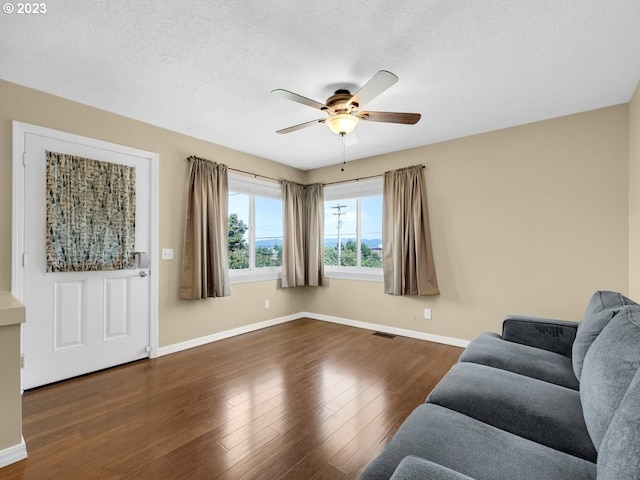 living room featuring a textured ceiling, ceiling fan, and dark hardwood / wood-style flooring