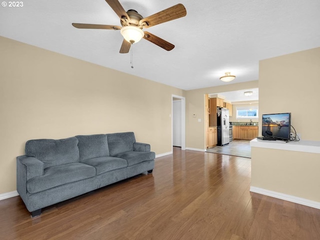 living room with ceiling fan, sink, and dark hardwood / wood-style floors