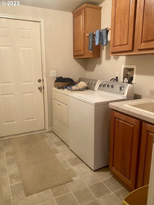 washroom featuring washing machine and clothes dryer, cabinets, and light tile floors