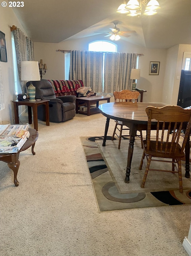 dining space featuring ceiling fan with notable chandelier, light carpet, and vaulted ceiling