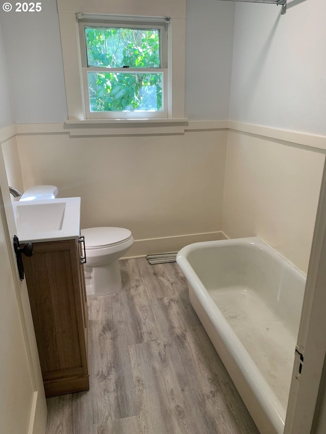 bathroom featuring vanity, hardwood / wood-style flooring, a tub, and toilet