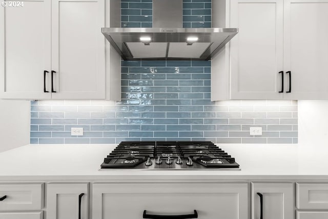 kitchen with wall chimney range hood, white cabinets, tasteful backsplash, and black gas stovetop