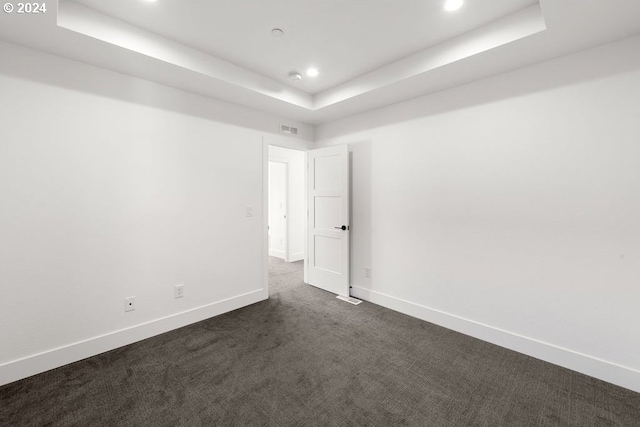 carpeted empty room with a raised ceiling