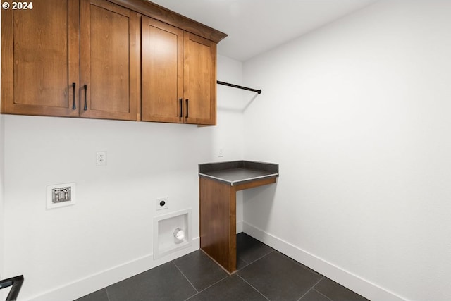 washroom with hookup for an electric dryer, dark tile patterned floors, and cabinets