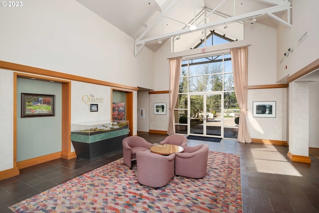 sitting room featuring dark tile floors and high vaulted ceiling