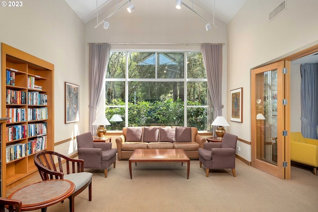 sitting room with track lighting, light colored carpet, high vaulted ceiling, and french doors