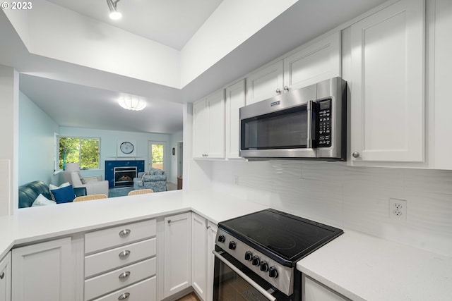 kitchen featuring backsplash, kitchen peninsula, white cabinets, and appliances with stainless steel finishes