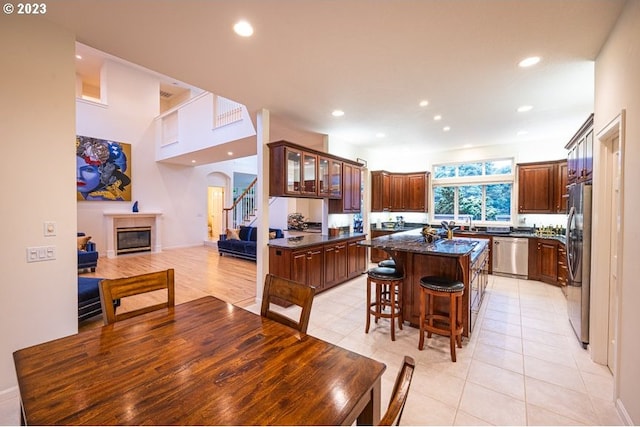 kitchen featuring light tile patterned floors, stainless steel appliances, a center island, and a breakfast bar area