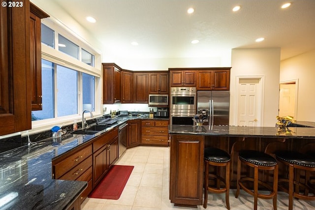 kitchen featuring a kitchen island, dark stone countertops, sink, light tile patterned floors, and appliances with stainless steel finishes