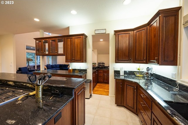 kitchen featuring light tile patterned flooring, sink, and dark stone counters