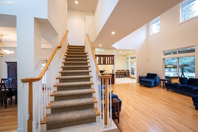 stairs with a high ceiling, a notable chandelier, and hardwood / wood-style flooring