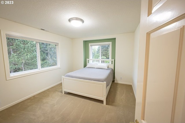 bedroom with a textured ceiling and light colored carpet