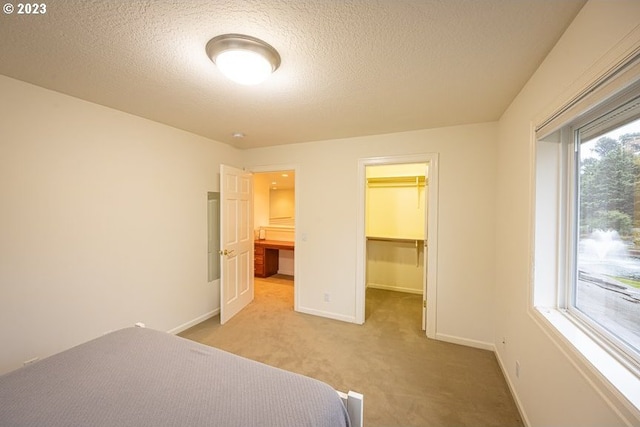 unfurnished bedroom featuring a spacious closet, carpet, a closet, and a textured ceiling