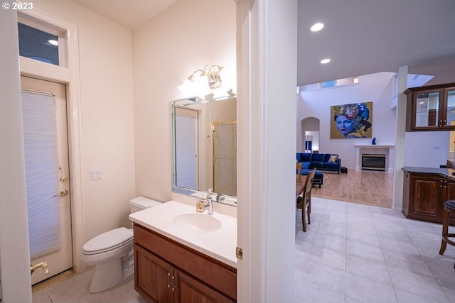 bathroom with toilet, a shower, vanity, and tile patterned floors