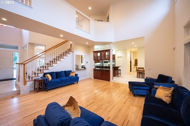 living room with a towering ceiling and light wood-type flooring