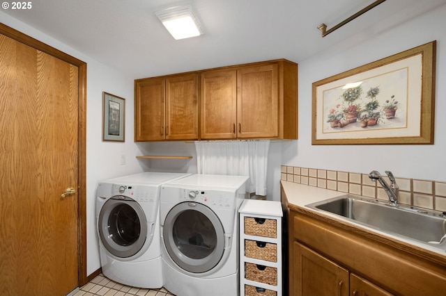 laundry area with a sink, light tile patterned floors, cabinet space, and washing machine and clothes dryer