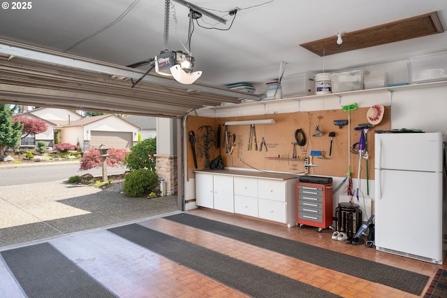 garage with a workshop area, a garage door opener, and freestanding refrigerator