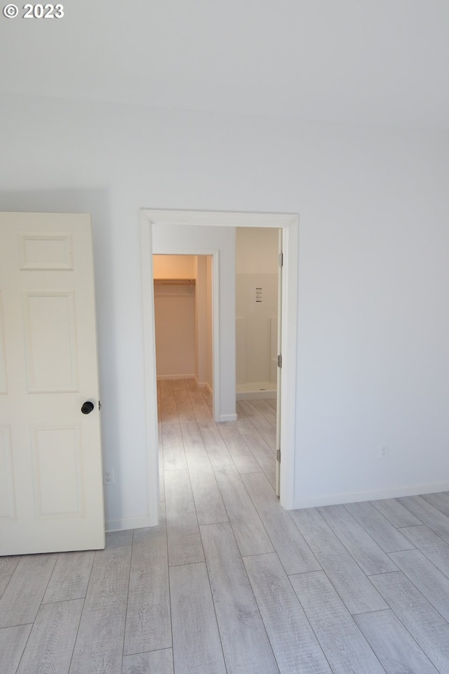 corridor with light wood-style flooring and baseboards