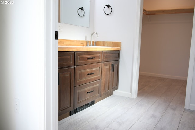 bathroom featuring baseboards, visible vents, a walk in closet, and vanity