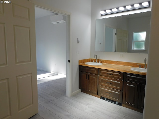 full bathroom with double vanity, a wall mounted AC, a sink, and wood finish floors