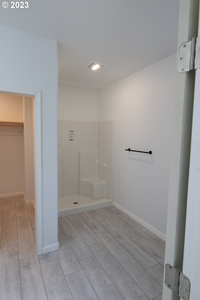 bathroom with a shower, visible vents, a spacious closet, wood tiled floor, and baseboards