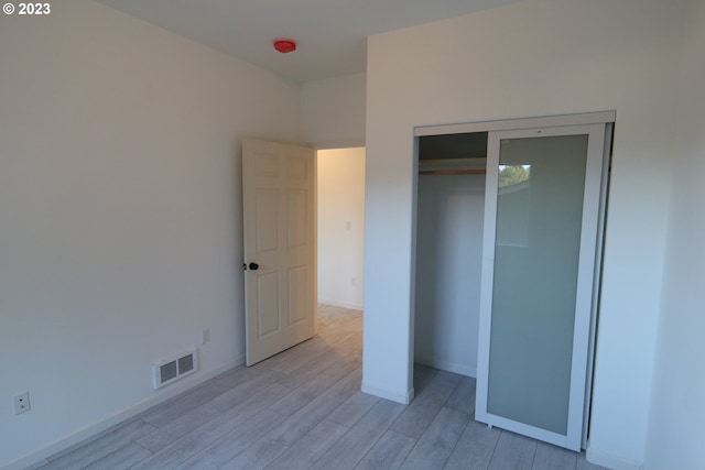 unfurnished bedroom featuring a closet, visible vents, baseboards, and light wood finished floors