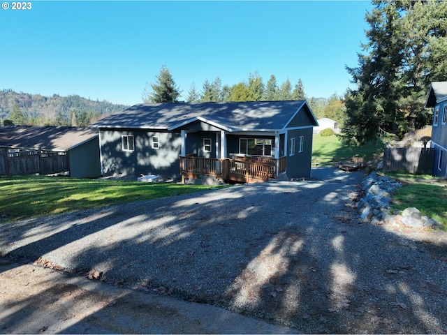 bungalow-style home featuring a wooden deck, fence, driveway, and a front lawn